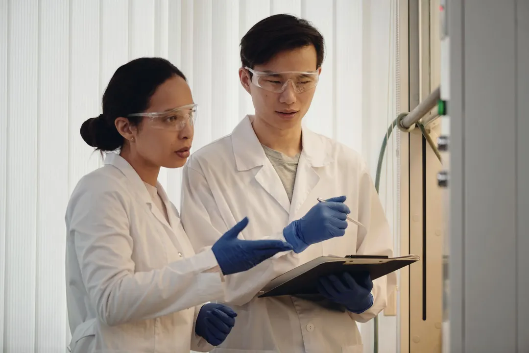 Two scientists in lab coats talk through a result.