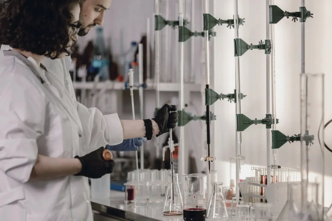 Two researchers set up an experiment at a long laboratory bench.