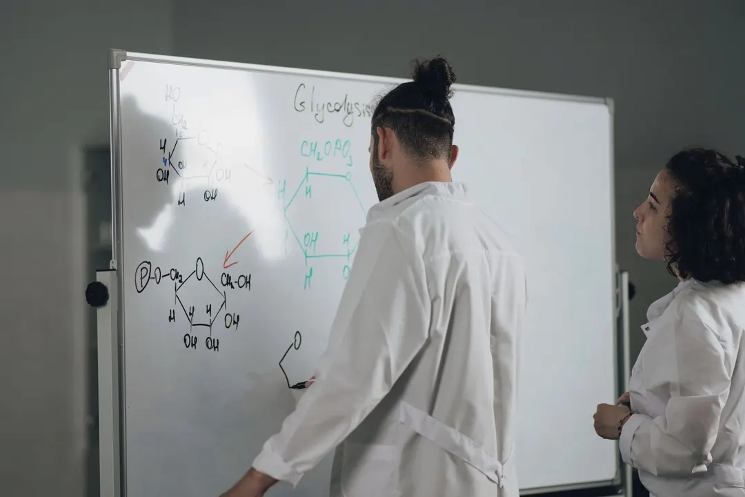A scientist works through a reaction on a whiteboard.